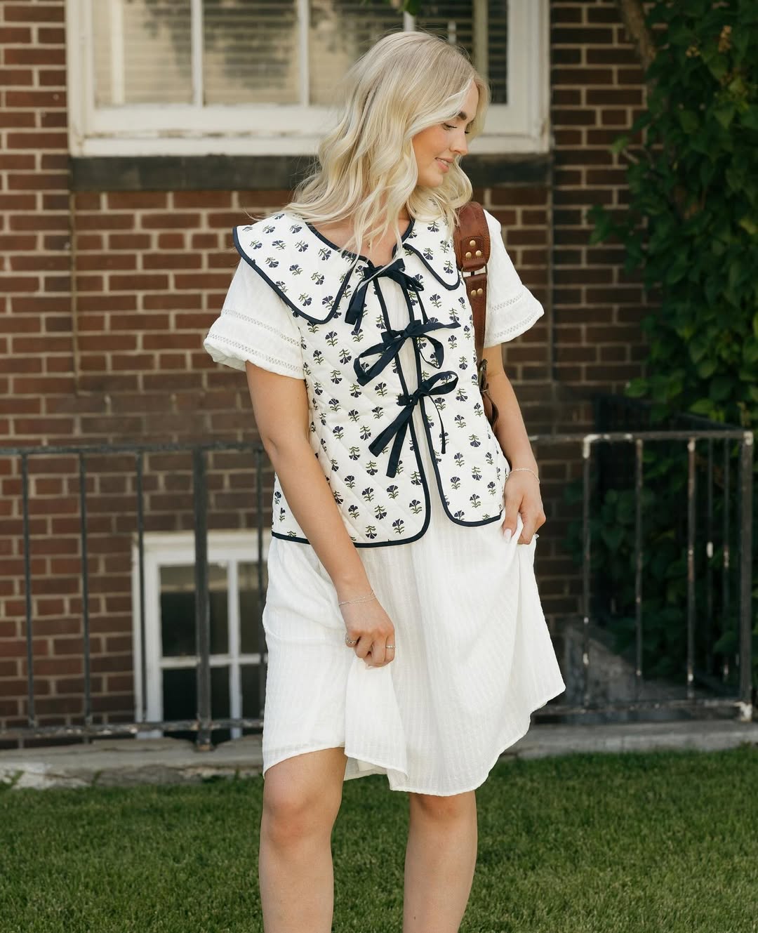 Quilted Vest Over White Dress With Brown Backpack