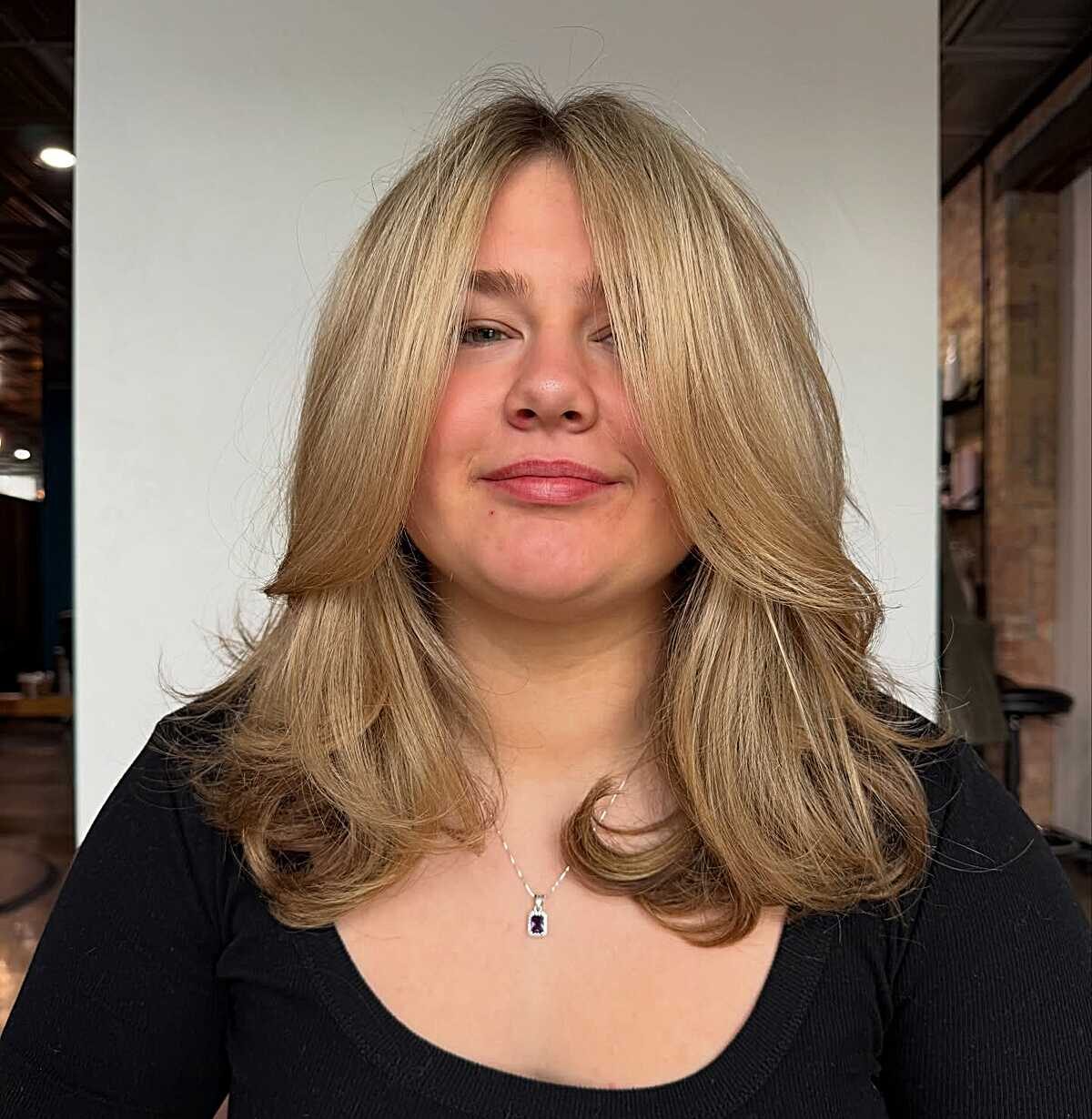 Golden blonde voluminous blowout with curtain bangs