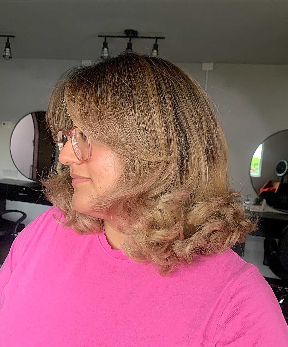 Honey blonde curly blowout with wispy bangs