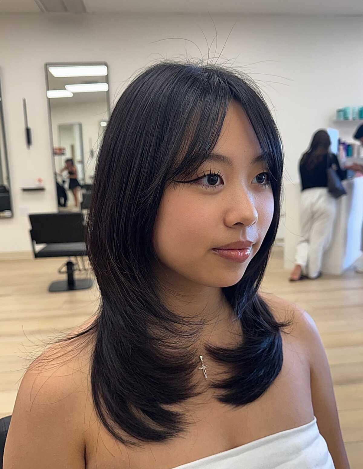 Sleek black layered blowout with long side bangs