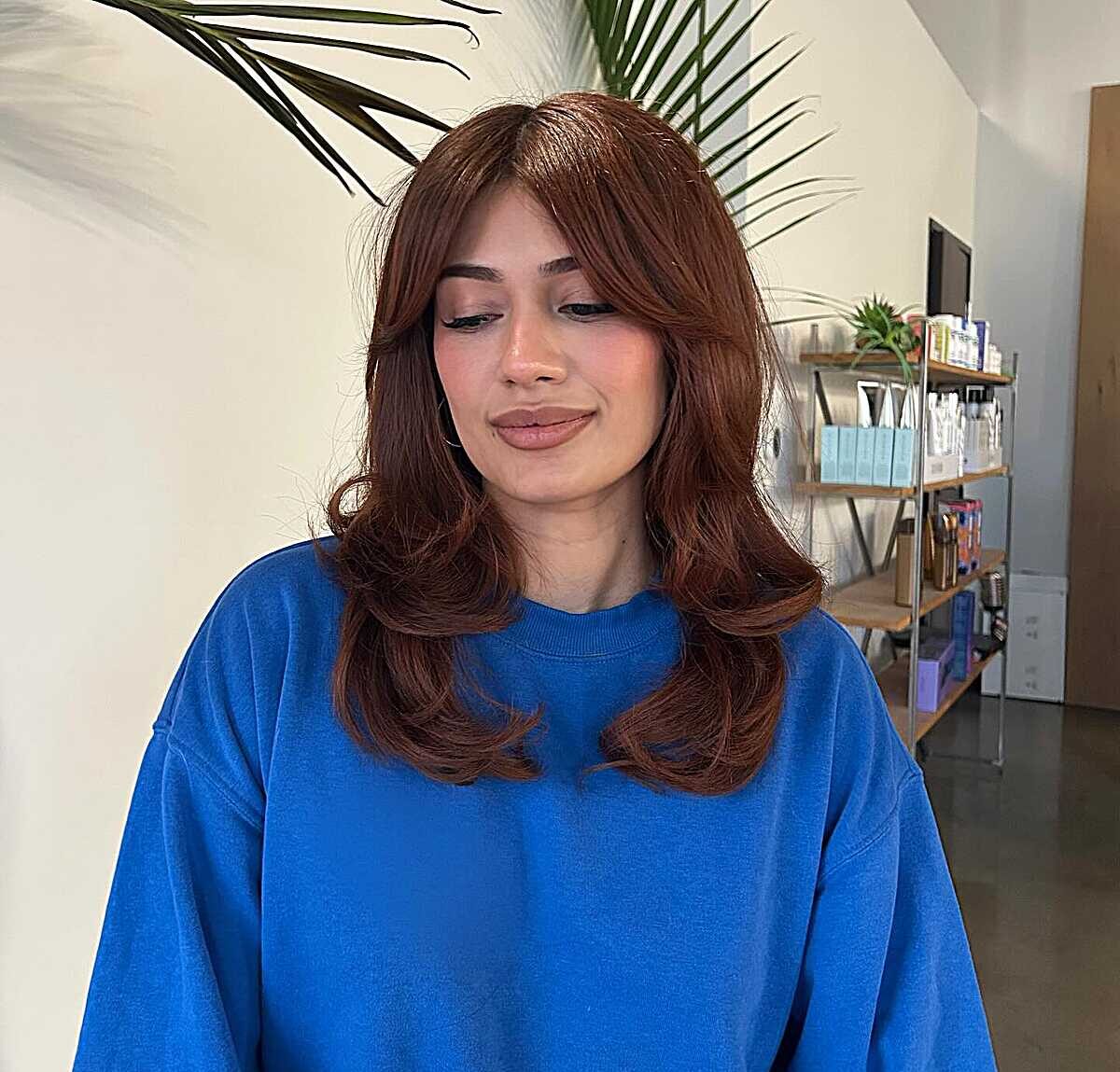 Warm auburn mid-length blowout with curtain bangs