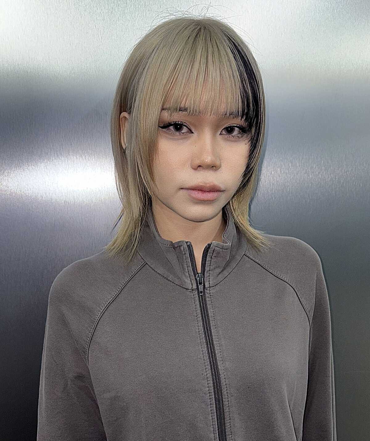 Chin-length blonde bob with a black streak near the ear