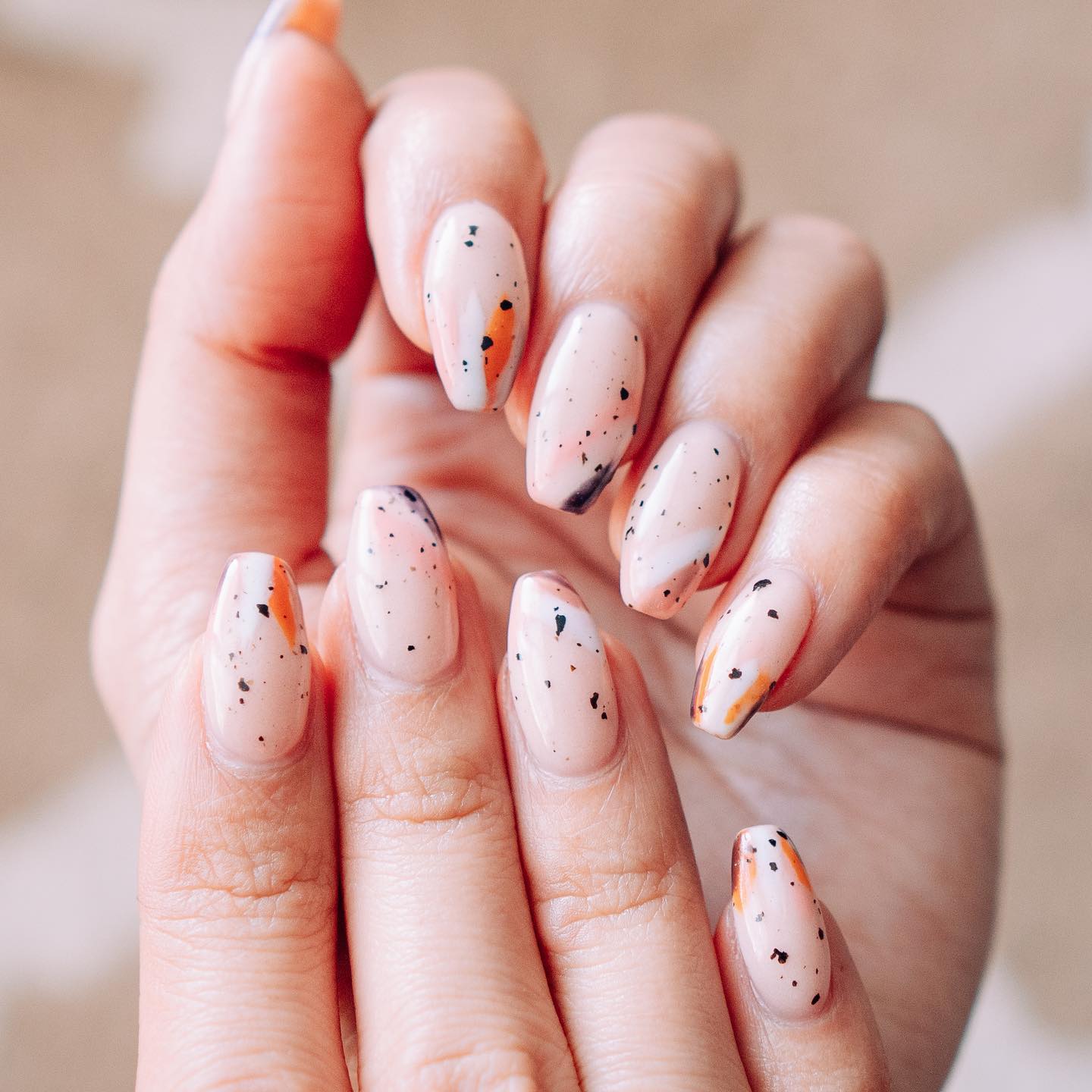 Speckled Pastel Oval Nails with Orange Accents