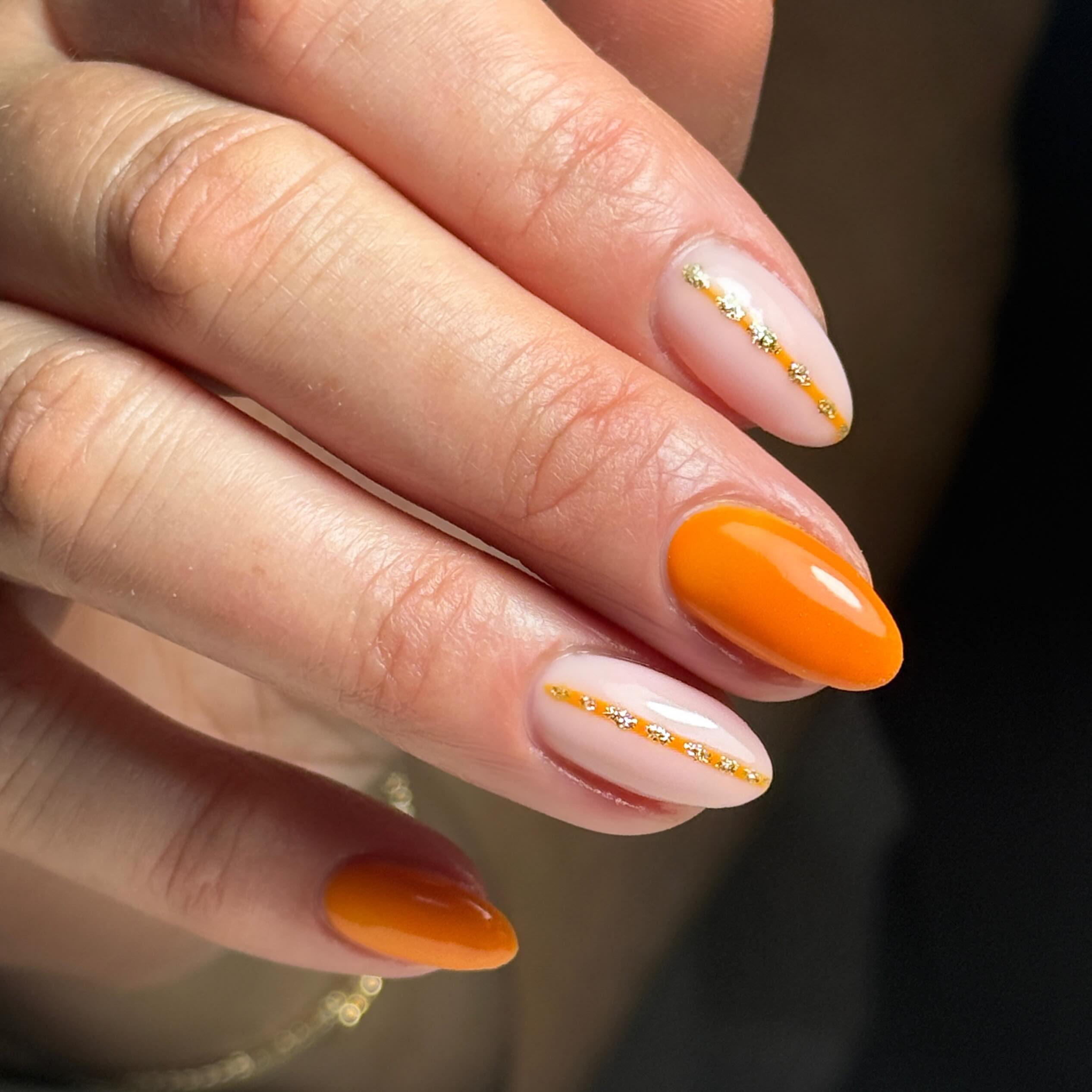 Gleaming Orange Almond Nails with Gold Stripe Accent