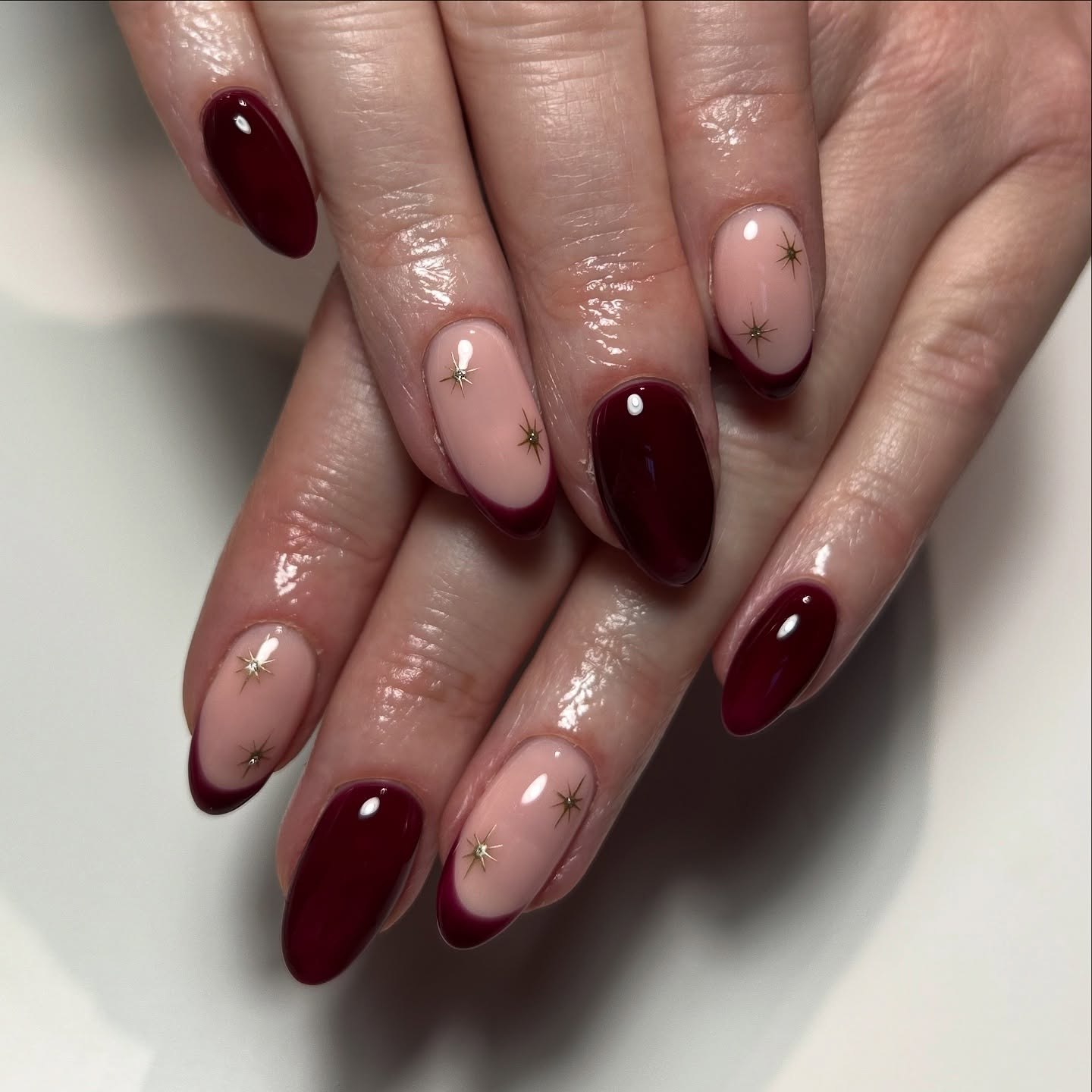 Deep Burgundy French Tip Oval Nails with Gold Stars