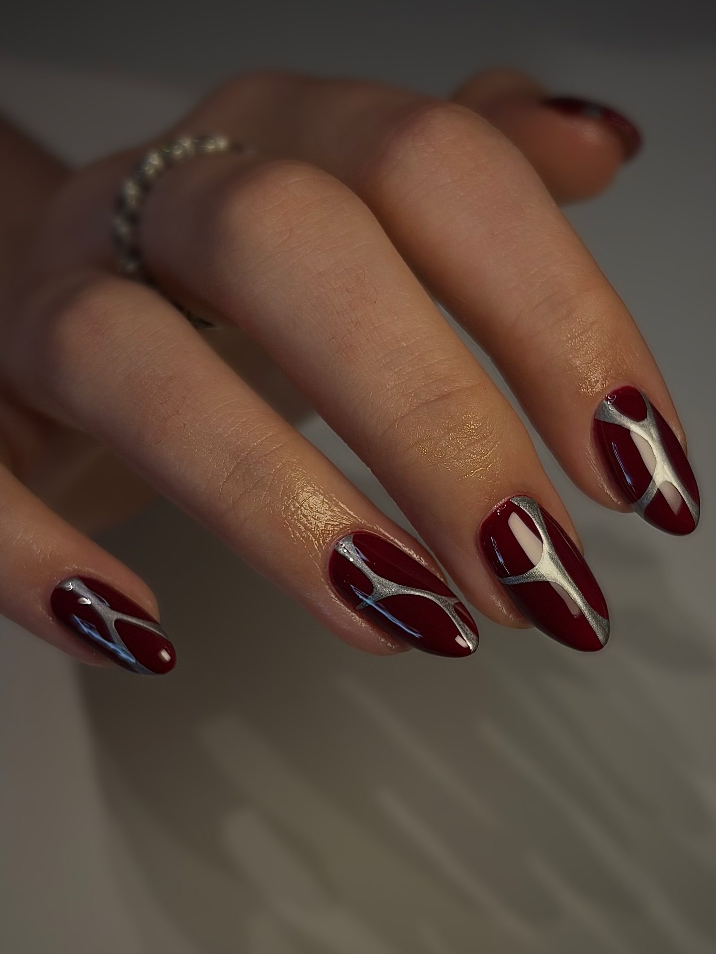 Glossy Burgundy Almond Nails with Silver Swirl Art