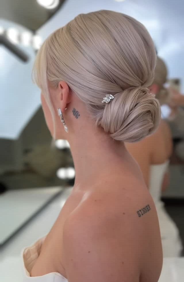 Icy Pearl Blonde Low Bun With Curtain Bangs — Low Bun Wedding Hair
